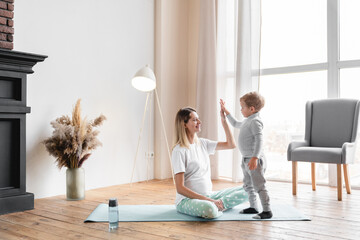 Young pregnant mother mom exercising on fitness mat with her little small kid son, giving high...