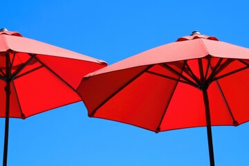 Vibrant Red Patio Umbrellas Framed Against a Clear Blue Sky from Below