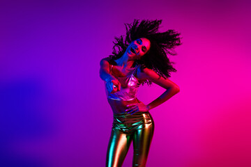 Energetic Young Woman in Glamorous Outfit Dancing in Neon Party Lighting