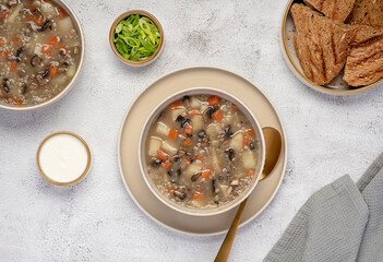 Food photography of mushroom soup with barley and vegetables, carrots; potatoes, spring onion, cream, toasted bread, vegetarian healthy food