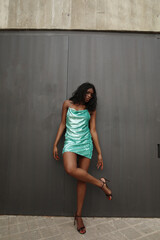 Fototapeta premium Vertical portrait of beautiful and young, African American woman wearing green dress posing outdoor.