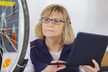 senior woman bicycle engineer repairing bike in workshop