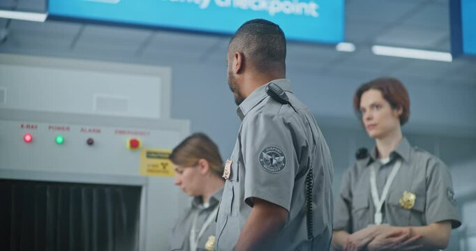 Airport Security Checkpoint: African American Security Officer Instructs Airport Staff About Scanning Process in X-ray Metal Detector Scanner and TSA Screening Procedures before Boarding Flight.