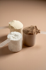 Chocolate, vanilla protein powder in scoops. Food supplement, fitness sport, health and nutrition.