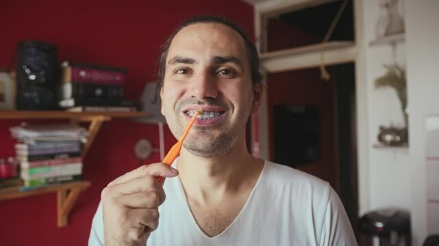 Close-up of male mouth with braces on teeth. Procedure of cleaning braces with a brush.