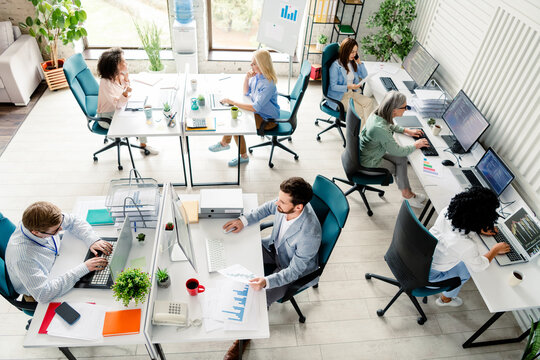 Professional team collaborating in a modern coworking space with daylight atmosphere, top view
