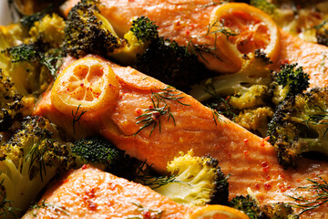 Close-up view of baked salmon fillets with broccoli and lemon, focus on the center