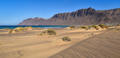 Playa de Famara dunes, beach, ocean and mountains panorama landscape, Lanzarote, Canary Islands. Travel Europe.