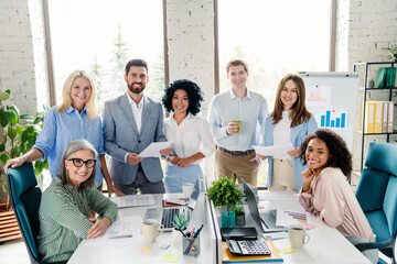 Diverse business team collaborating in modern office setting with paperwork and data charts