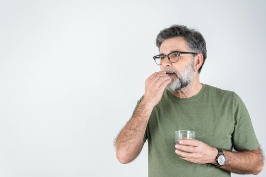 Man taking medication. Painful old age. Caring for the health of the elderly bearded man.