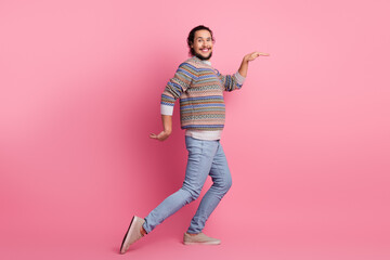 Smiling young man posing playfully in trendy sweater against vibrant pink background, showcasing...