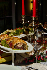 a beef wellington on a celebration table with silver chandelier and red candles