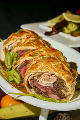 a beef wellington with sauce on a white plate 