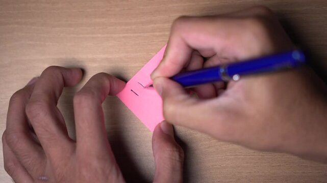 Expressing negative feelings on a pink sticky note with a pen, wooden background