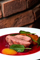 a red meat steak with vegetables and red sauce on a white plate 