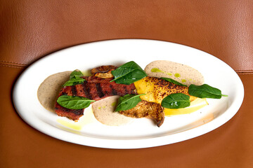 a red meat steak with vegetables and sauce on a white plate 