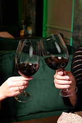 people are cheering with two glasses of red wine on a green background 