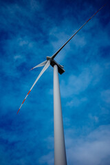 White wind turbine rotor against a blue sky background. Electric generator photographed from below