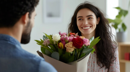 Smiling woman receives a bouquet of flowers from a man in a cozy indoor setting