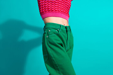 Young woman in vibrant pink and green attire posed against a teal background emphasizing colorful fashion
