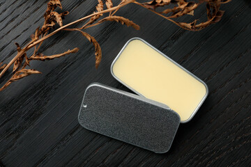 Natural solid perfume and dry branch on black wooden table, flat lay