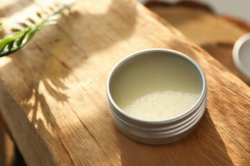 Natural solid perfume in container on wood, closeup