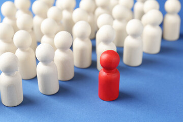 Obraz premium Competition concept. Red human figure ahead of other ones on blue background, closeup
