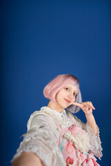 Cosplayer taking a selfie wearing pastel kawaii clothes with pink and violet hair