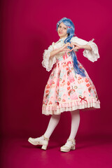 Cosplayer making heart shape with hands wearing sweet lolita fashion dress and blue wig