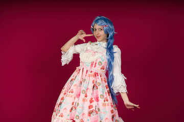 Cosplayer wearing colorful dress and blue wig is framing her face with fingers