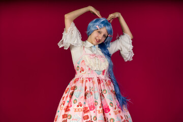 Cosplayer making heart shape with hands and smiling on red background