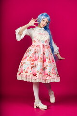 Cosplayer wearing colorful lolita fashion dress and posing on pink background