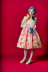 Cosplayer wearing colorful lolita dress posing on pink background