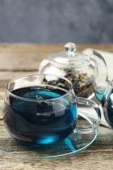Delicious butterfly pea flower tea on wooden table against gray background