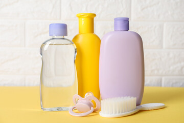 Baby oil and bath accessories on yellow table