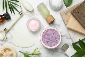 Flat lay composition with different body care products and flowers on white marble table