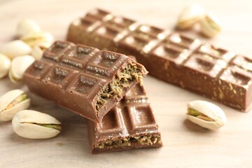 Delicious Dubai chocolate bars and pistachios on wooden table, closeup
