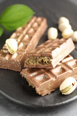 Delicious Dubai chocolate bars and pistachios on table, closeup