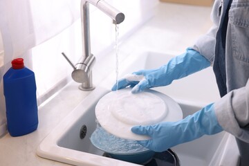 Woman washing dishes in kitchen sink, closeup