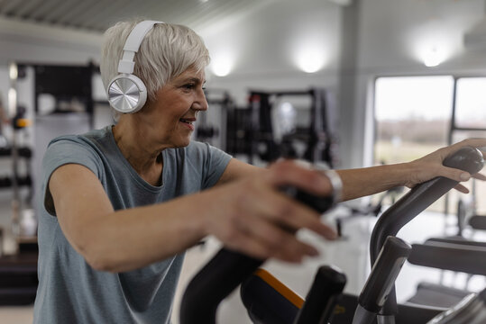 Older woman exercising on elliptical in modern gym