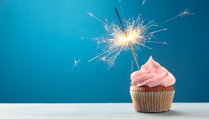 happy birthday celebration cupcake with burning sparkler on a wooden surface, copy space