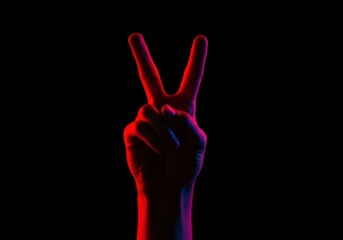 Obraz premium A futuristic depiction of the peace hand gesture under intense red and blue lights, creating a bold contrast.