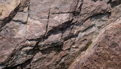 Fototapeta premium Weathered purple rock texture, background. Rough, fractured stone in muted purple and brown tones, with deep crevices and fine cracks, revealing the effects of erosion on metamorphic rock surfaces