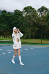 Young athlete in stylish sportswear walking on a tennis court, showcasing confidence and...