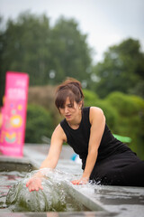 Woman happily splashing water at the fountain in front of the camera