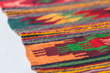 Close-up image of intricate, colorful traditional woven textile Depicts various hues blue, green,...