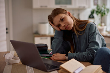 Bored female student using computer while e-learning at home.