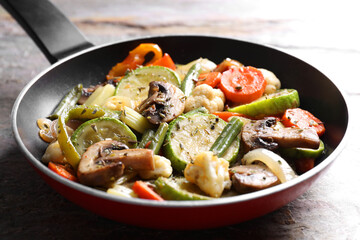 Different vegetables and mushrooms in frying pan on grey textured table, closeup