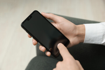 Man using smartphone with blank screen indoors, closeup