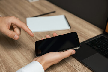 Man using smartphone with blank screen at wooden table, closeup